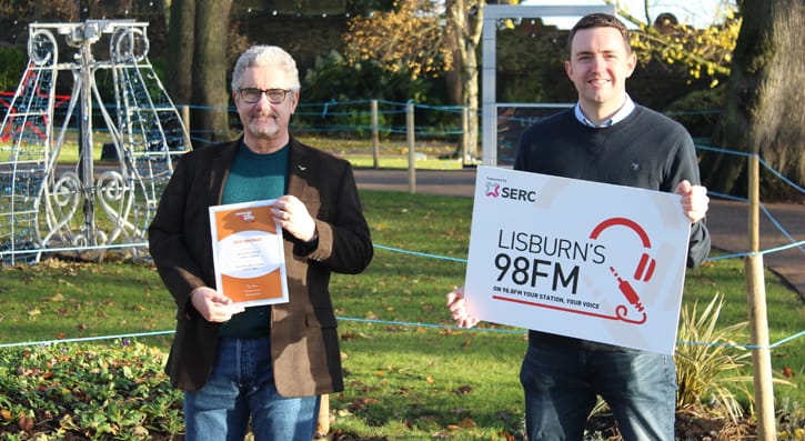 Davy Sims holding his award, with Michael Clarke holding a Lisburn's 98FM board.